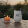 White wine tumbler with text on a wooden table with a candle in the background