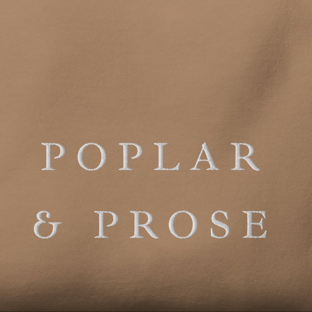 Folded brown shirt with 'Poplar & Prose' embroidered in white
