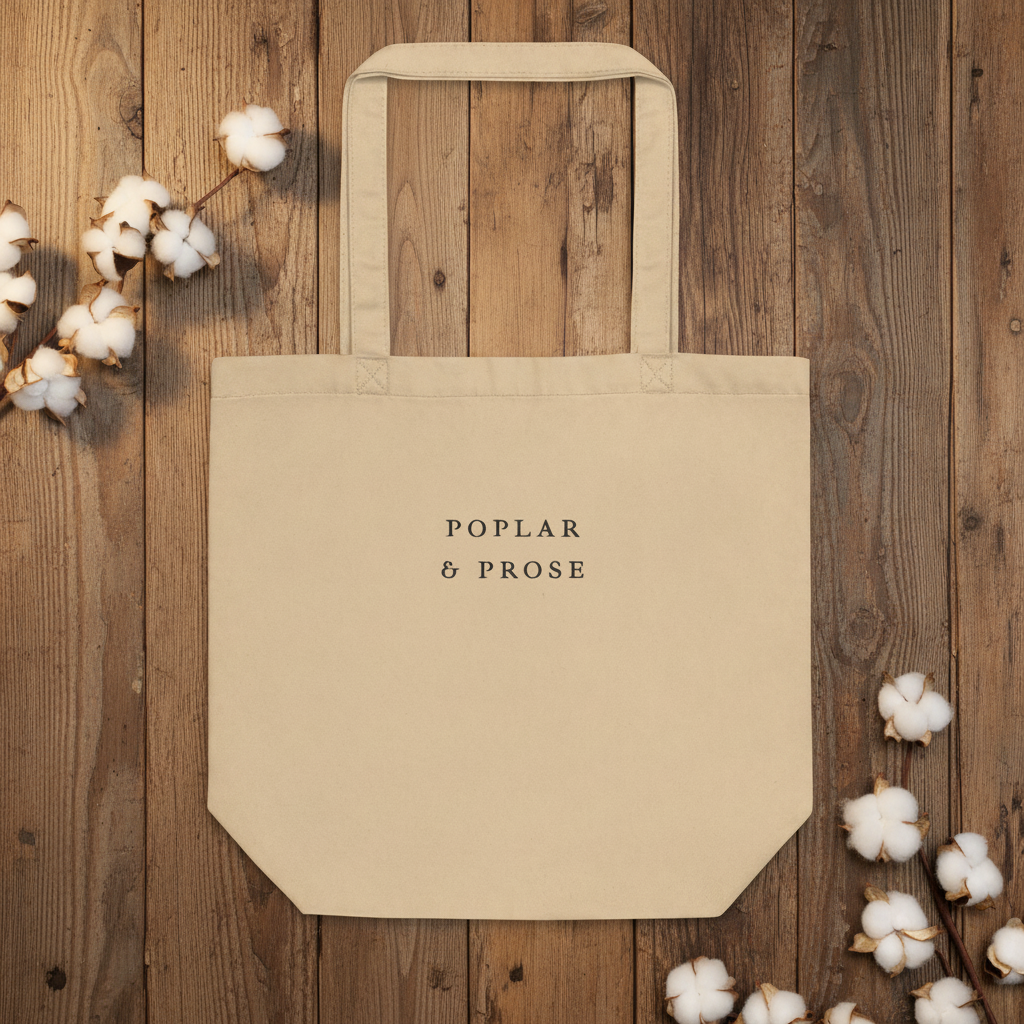 Beige tote bag with 'Poplar & Prose' text on a wooden background with cotton flowers.