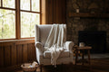 Beige and brown striped blanket with tassels draped over a women in beige chair